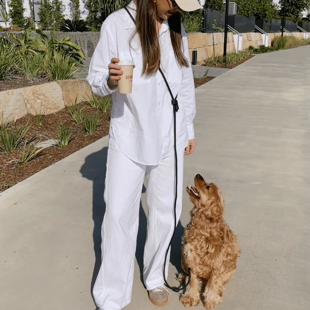 Dog owner using black hands-free dog lead cross-body style, practical and comfortable walking accessory