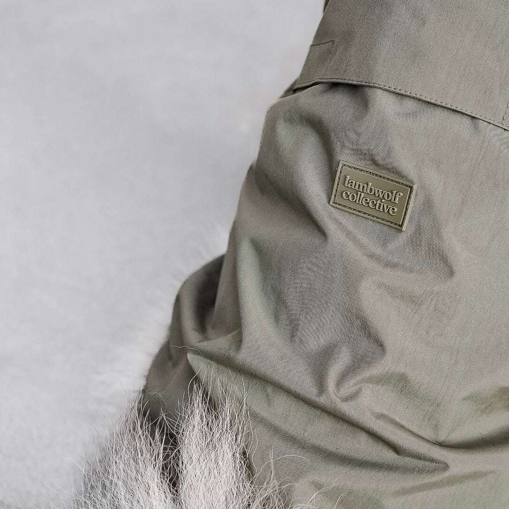 Close-up of Lambwolf Collective dog raincoats showing back detail and brand tag, modern minimalist style