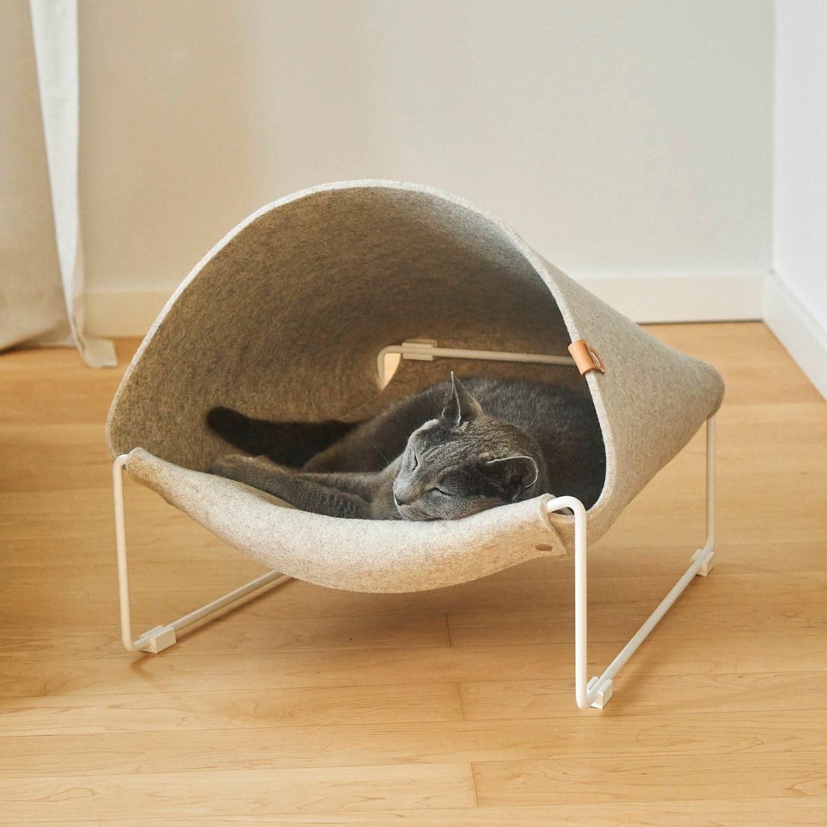 Cat lounging inside MiaCara Loggia felt cat cave, modern raised hideaway with cozy enclosed design.