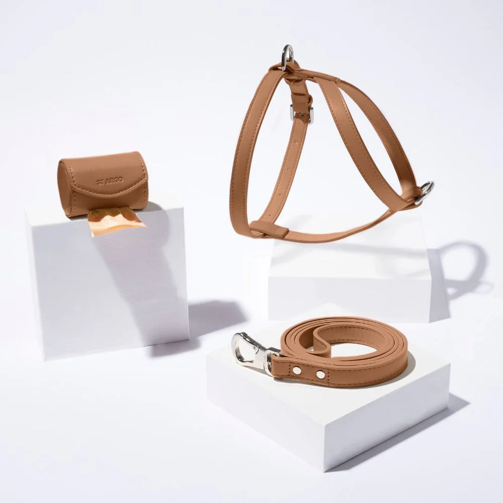 Brown vegan leather dog harness, leash and poop bag holder set on a white background