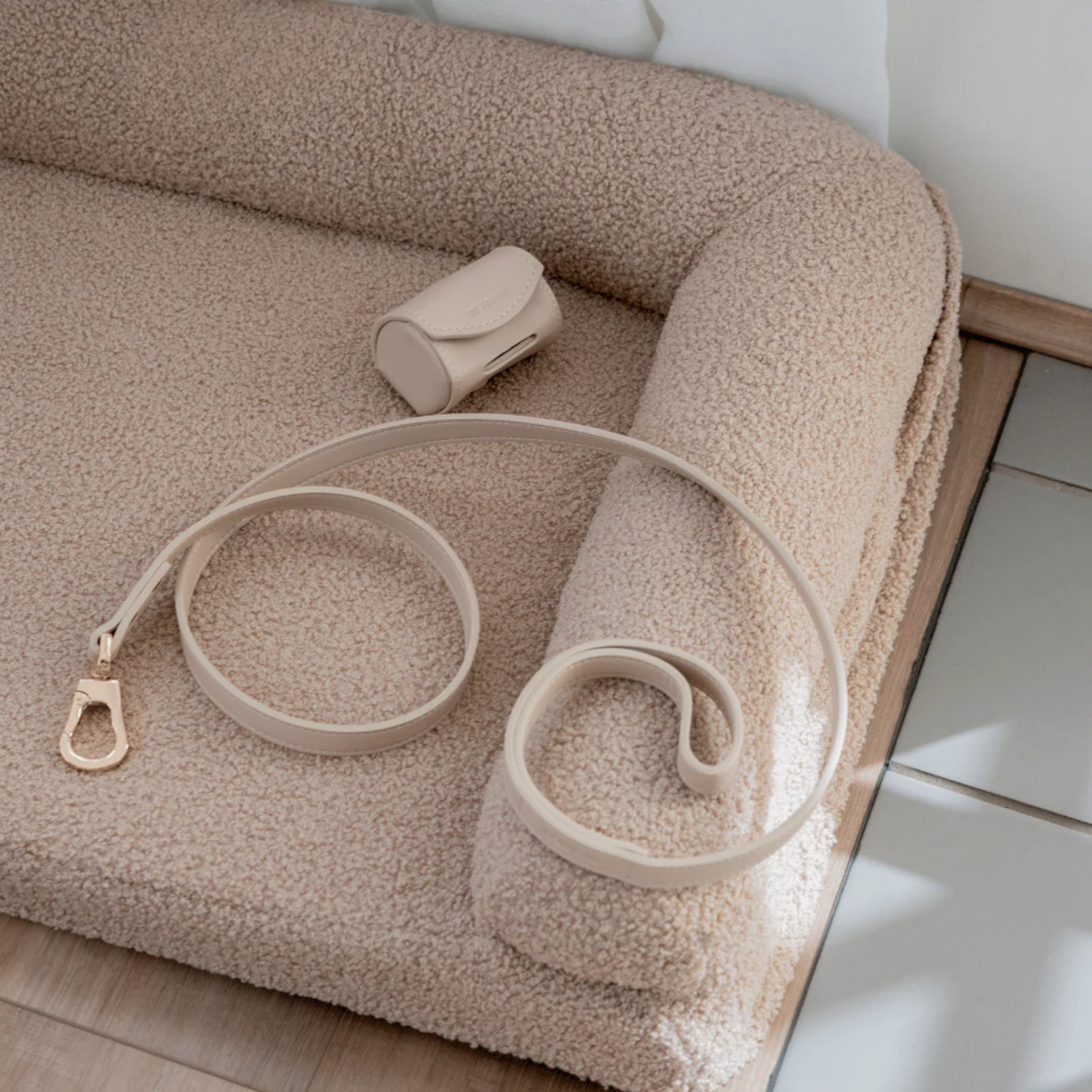 Beige vegan leather dog lead and poop bag holder on a textured surface