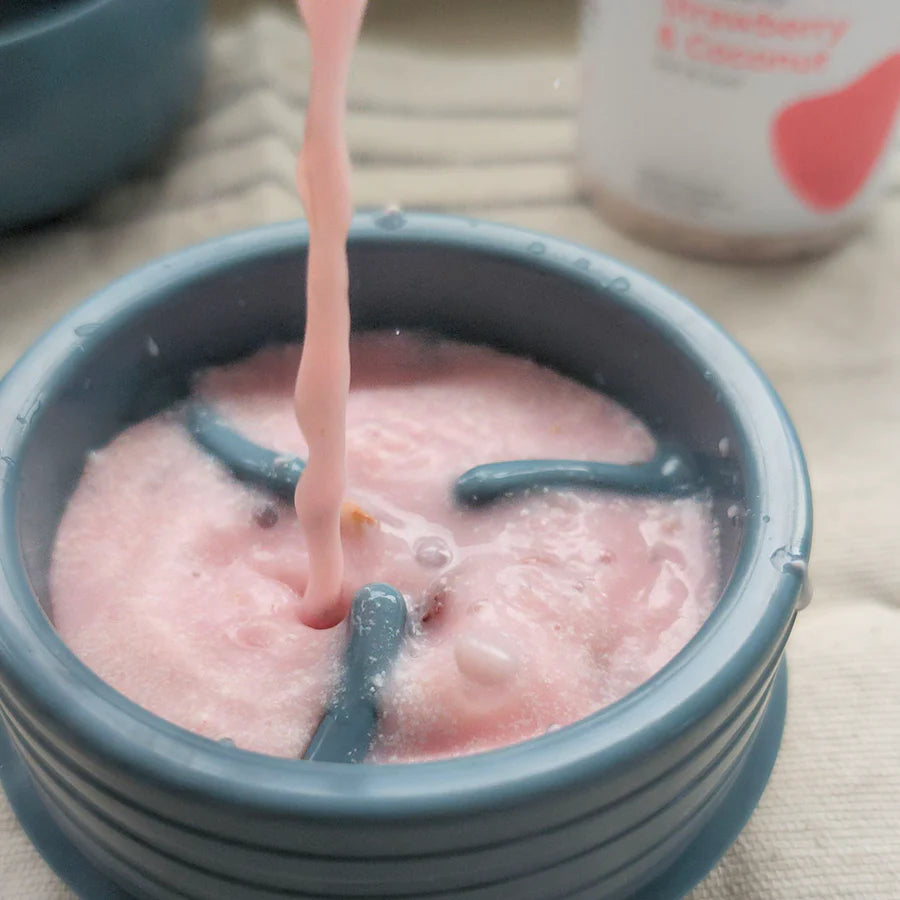 Lunoji Pebble interactive dog toy in slate blue being filled with pink smoothie-style treat, enrichment toy designed for slow feeding and mental stimulation.