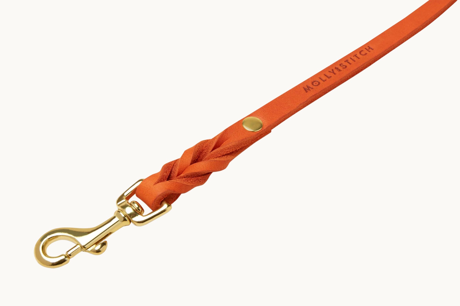 Close-up of Molly & Stitch orange butter leather leash, highlighting braided detail and polished gold clasp.