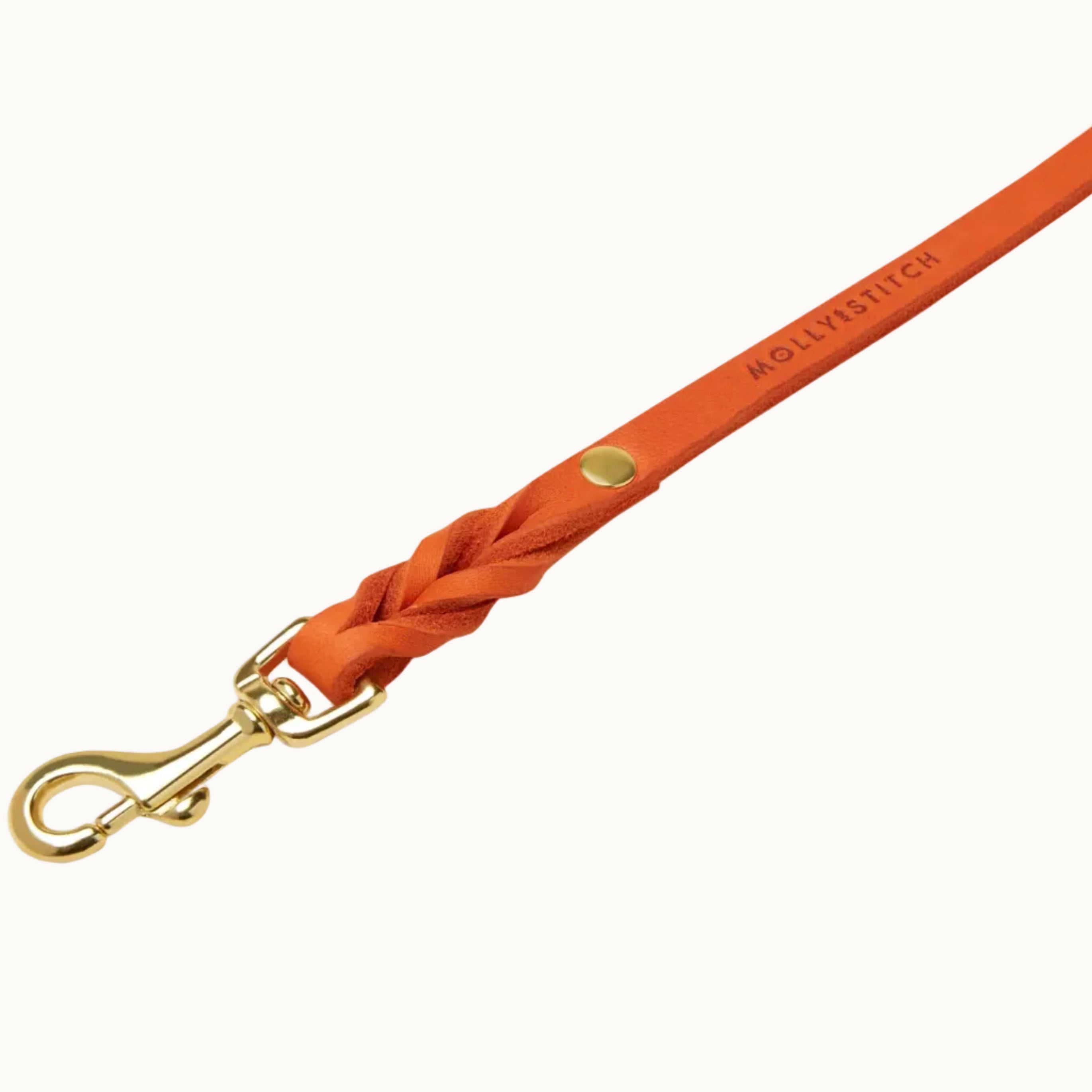 Close-up of Molly & Stitch orange butter leather leash, highlighting braided detail and polished gold clasp.