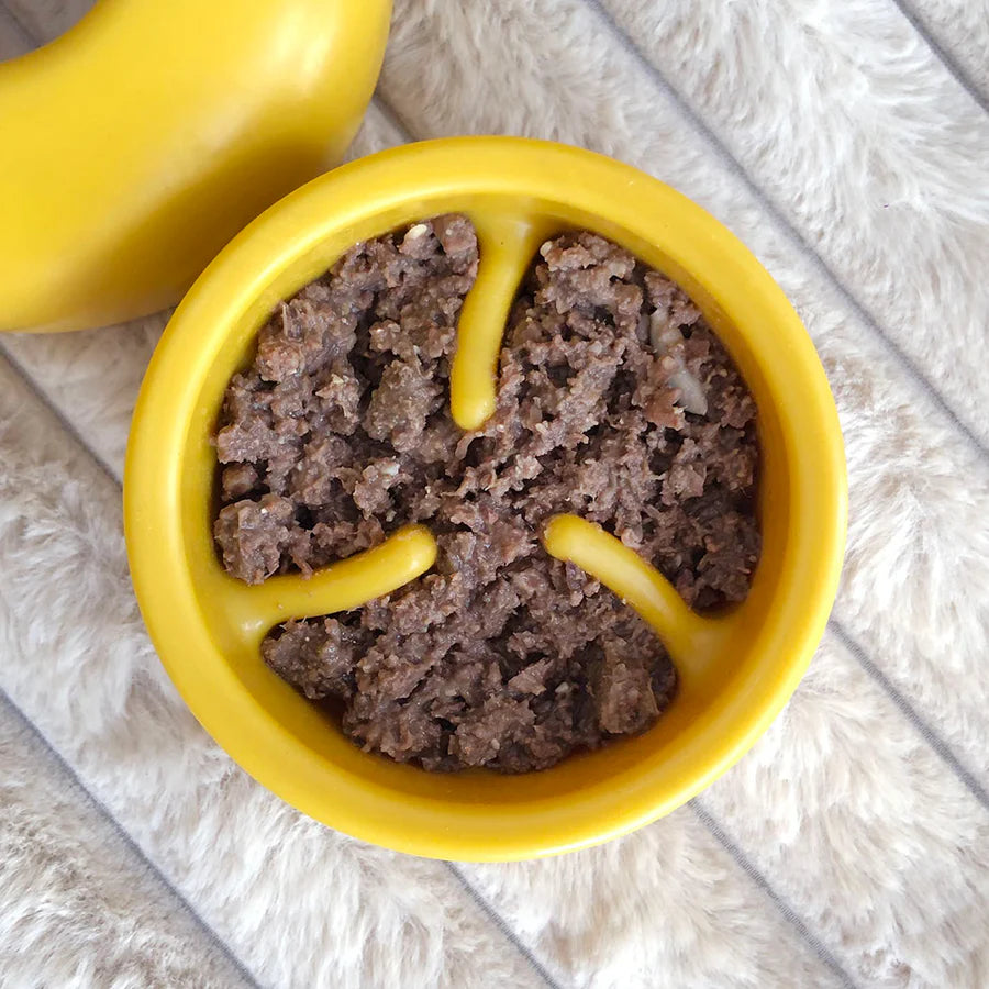 Close-up of Lunoji Pebble interactive dog toy in yellow showing inside filled with wet food. slowfeeder