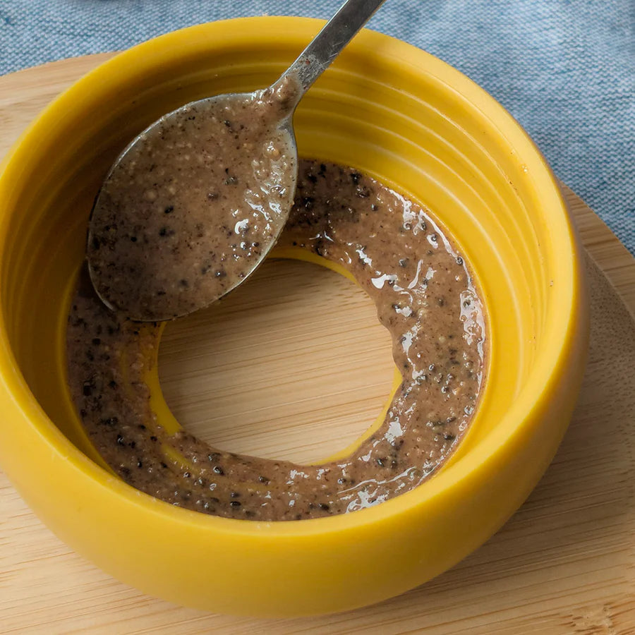Close-up of Lunoji Pebble interactive dog toy in yellow showing inside spreading with wet food. slowfeeder