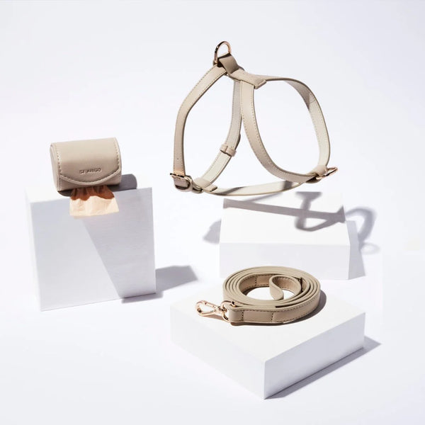 beige vegan leather harness, leash, and poop bag holder set on a white background